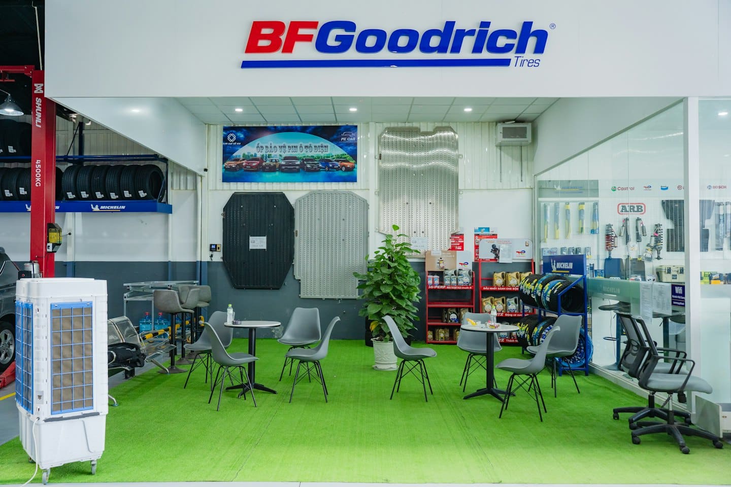 Moderna sala de espera de centro de servicio automotriz con bahías de servicio profesionales al fondo.