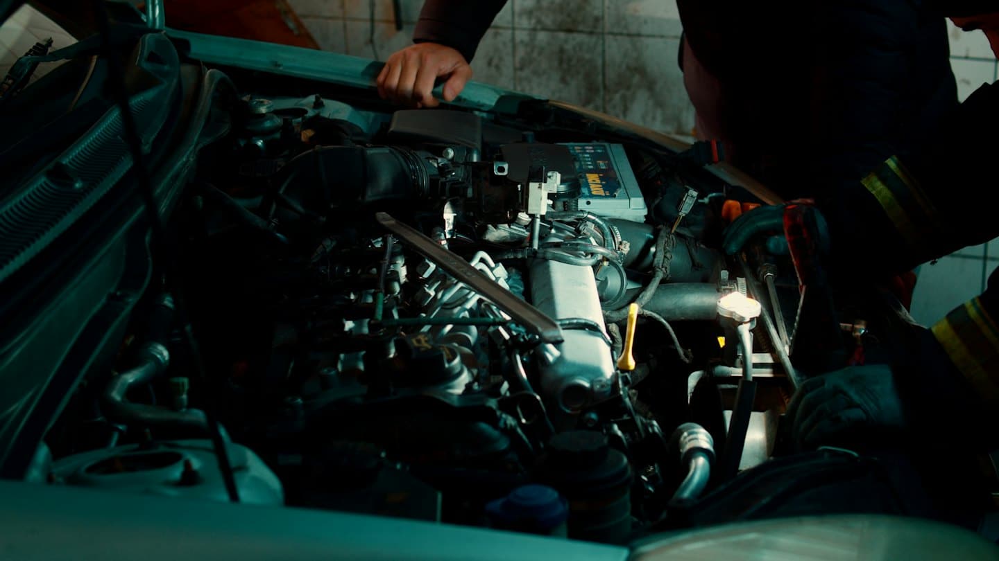 Manos de mecánico trabajando en el motor de un coche en un taller.