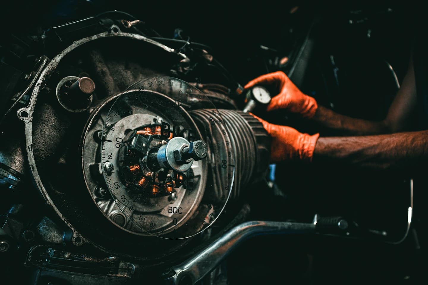 Manos enguantadas de mecánico trabajando en el motor de una motocicleta.